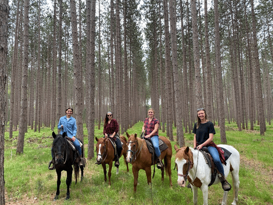 Four girls riding horses in the Manistee National Forest while visiting Wolf Lake Ranch. 