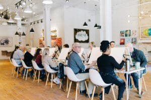 Group of people take a painting class at Brush Studios