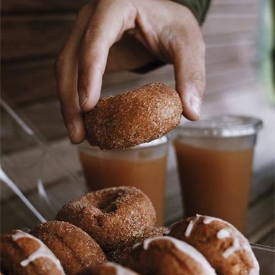 Michigander holding a donut and apple cider from an orchard